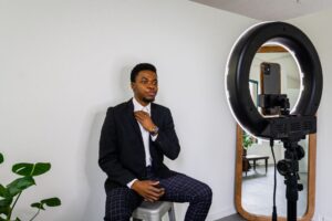 African fashion designer in studio with laptop displaying website.
